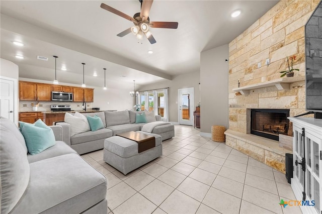 living area with visible vents, a stone fireplace, ceiling fan, and light tile patterned flooring