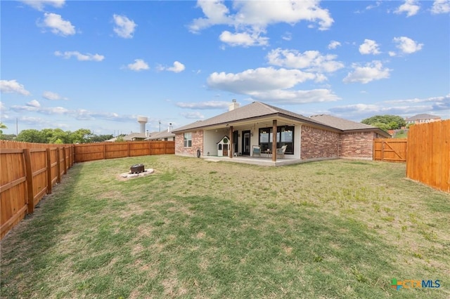 back of house featuring a yard, a patio, a fenced backyard, and an outdoor fire pit