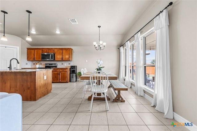 kitchen featuring visible vents, a sink, a chandelier, brown cabinetry, and appliances with stainless steel finishes