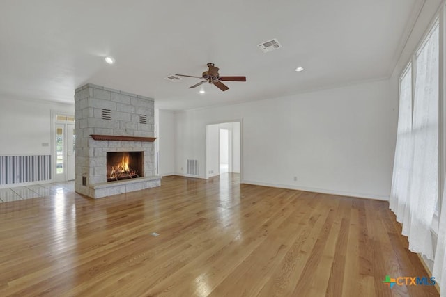 82 Bell Mountain Rd, Fredericksburg, TX 78675 - unfurnished living room featuring a ceiling fan, light wood-style flooring, a stone fireplace, recessed lighting, and crown molding