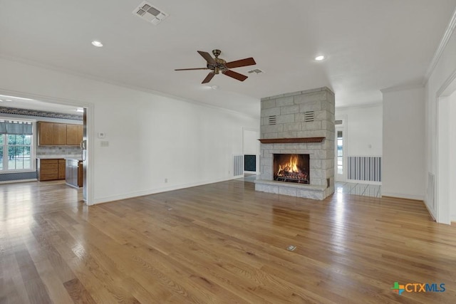 82 Bell Mountain Rd, Fredericksburg, TX 78675 - unfurnished living room with ornamental molding, ceiling fan, a stone fireplace, light wood-type flooring, and recessed lighting