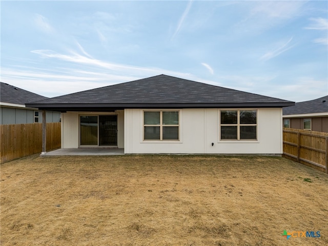 back of house with a patio and a lawn