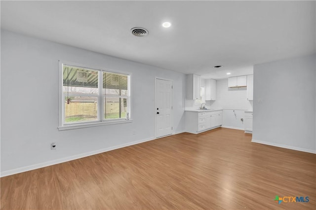 unfurnished living room featuring sink and light hardwood / wood-style flooring