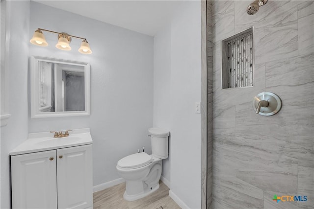 bathroom with vanity, a tile shower, and toilet