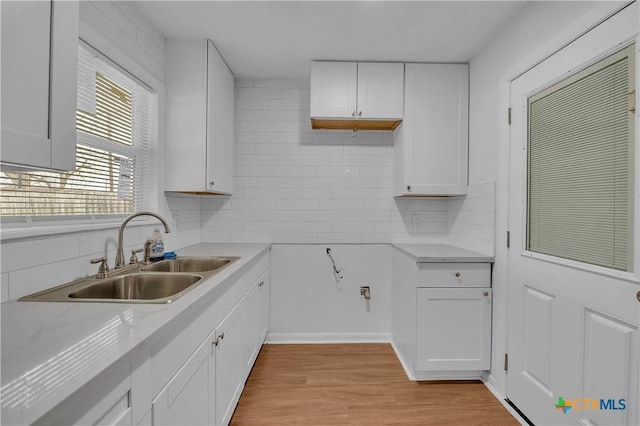 kitchen with white cabinetry, sink, tasteful backsplash, and light wood-type flooring