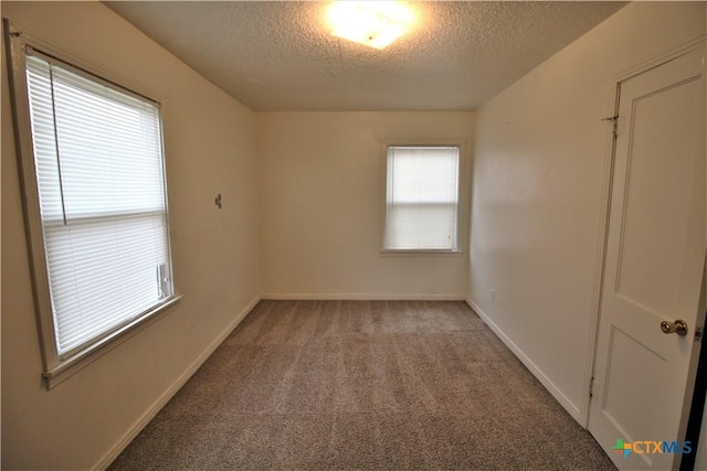 carpeted empty room with a textured ceiling