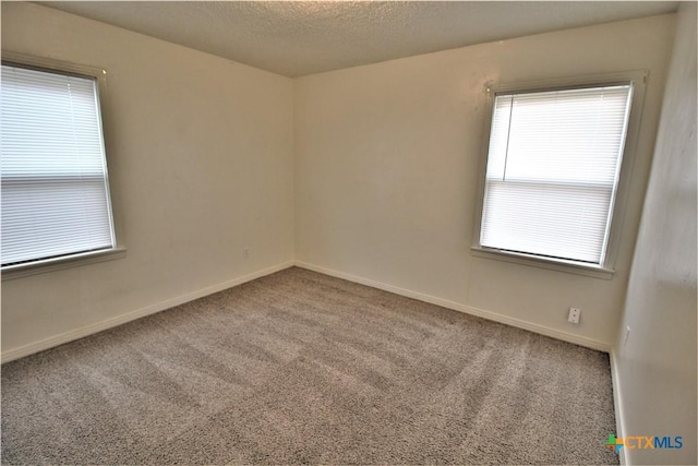 carpeted spare room featuring a healthy amount of sunlight and a textured ceiling