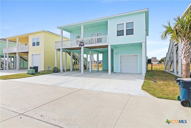 coastal home with central AC, a balcony, a garage, and a carport