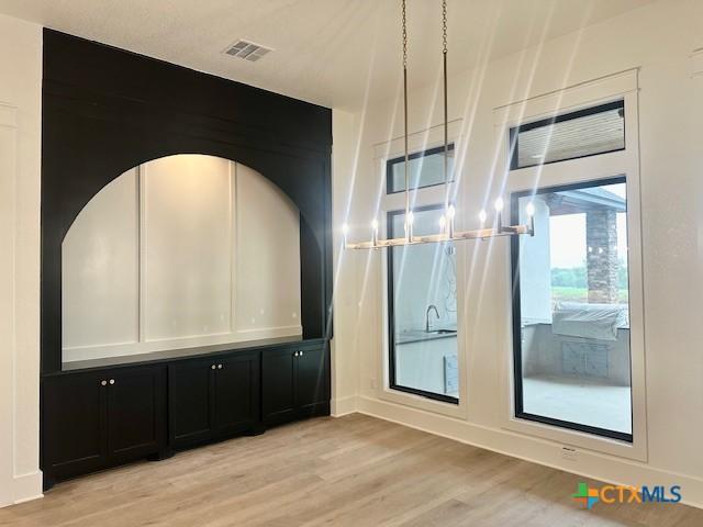 empty room with light wood-style floors and visible vents