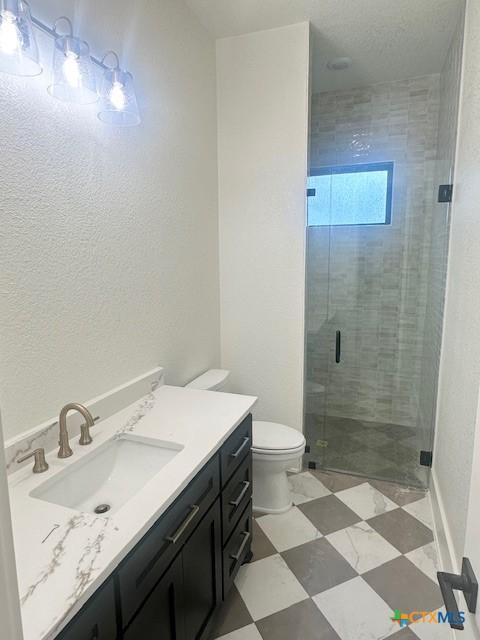 bathroom featuring toilet, tile patterned floors, vanity, and a stall shower