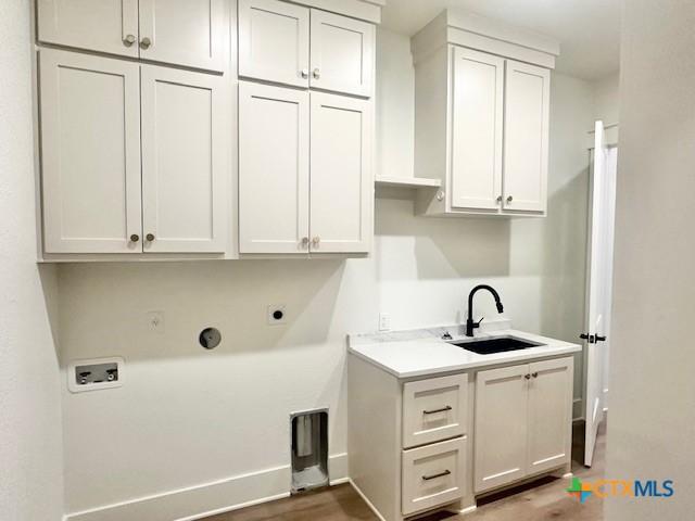 clothes washing area featuring hookup for a washing machine, electric dryer hookup, a sink, baseboards, and cabinet space