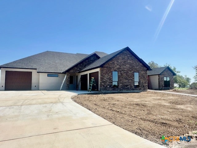 ranch-style house with an attached garage, stone siding, and driveway