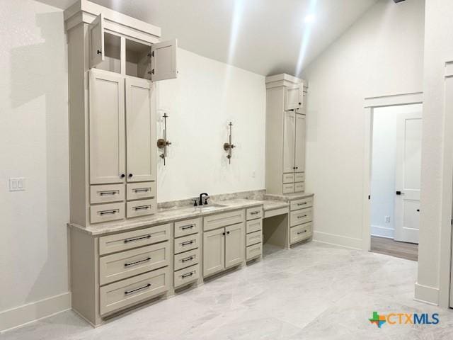 bathroom with vanity, baseboards, and vaulted ceiling