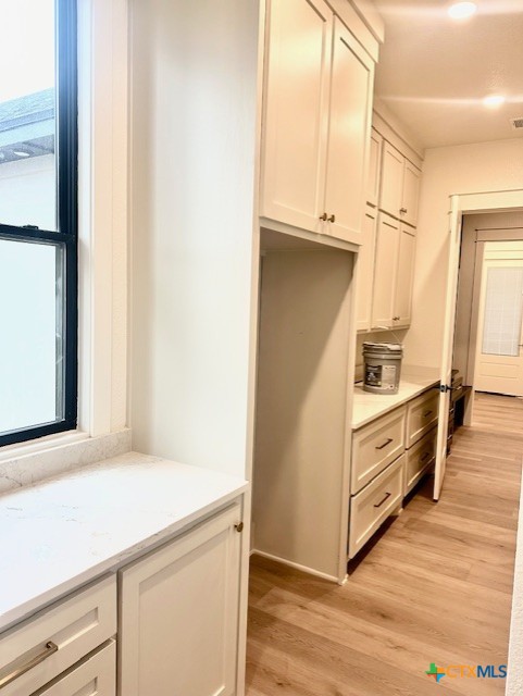 kitchen with light wood-style flooring, light countertops, visible vents, and white cabinetry