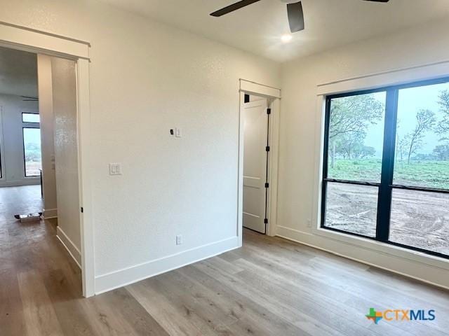 empty room with baseboards, a ceiling fan, and wood finished floors