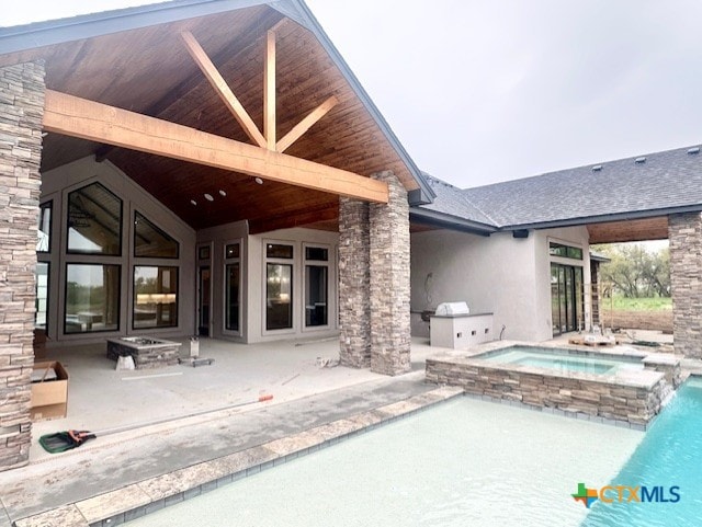 view of swimming pool with an outdoor kitchen, a patio area, and a pool with connected hot tub