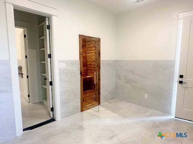 bathroom with wainscoting, visible vents, and tile walls