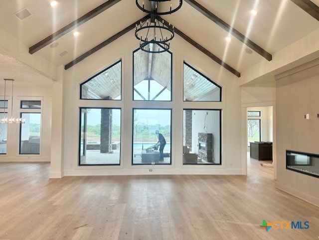 unfurnished living room with a chandelier, visible vents, light wood-type flooring, and beamed ceiling