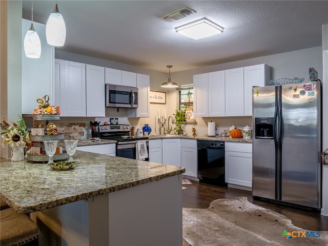 kitchen featuring white cabinetry, appliances with stainless steel finishes, hanging light fixtures, and stone countertops