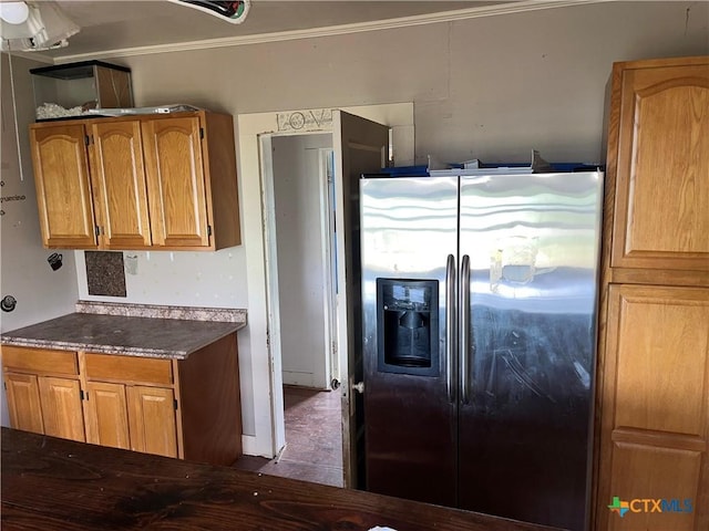 kitchen featuring refrigerator with ice dispenser, brown cabinets, dark countertops, and crown molding