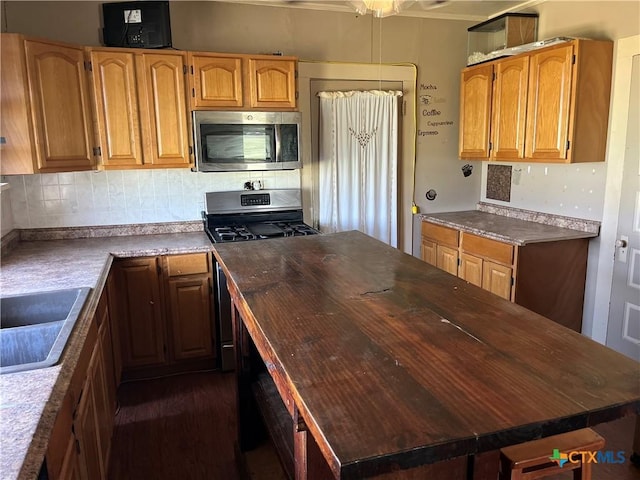kitchen with stainless steel appliances, a center island, dark wood-type flooring, tasteful backsplash, and crown molding