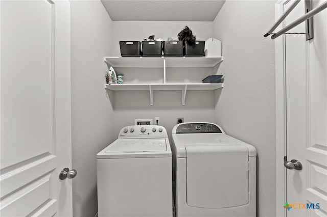 laundry room with a textured ceiling and washing machine and clothes dryer