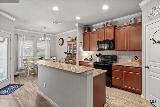 kitchen featuring decorative backsplash, black appliances, a chandelier, hanging light fixtures, and an island with sink