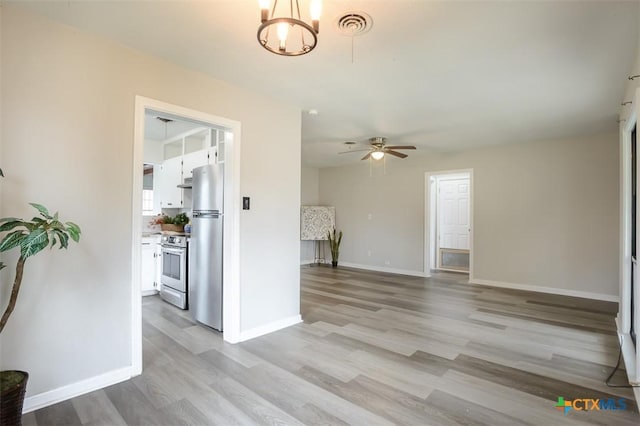 unfurnished living room featuring light wood-style floors, visible vents, baseboards, and a ceiling fan