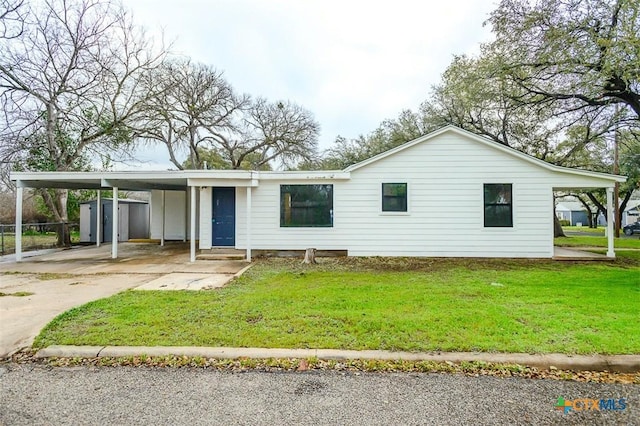 view of front of house with concrete driveway, an attached carport, a front yard, and fence