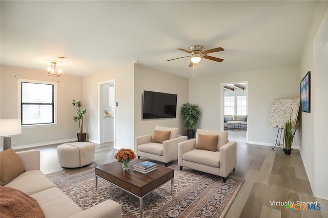 living area with ceiling fan, plenty of natural light, baseboards, and wood finished floors