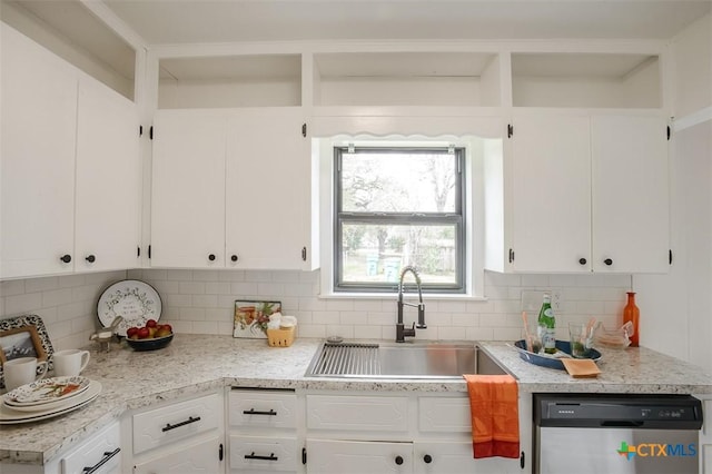 kitchen featuring tasteful backsplash, white cabinets, a sink, and stainless steel dishwasher