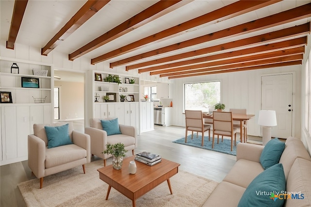 living area with light wood-style floors and beam ceiling