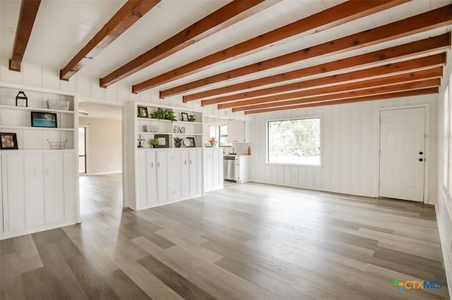 unfurnished living room featuring light wood-style flooring and beamed ceiling