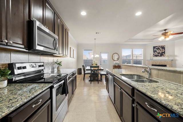 kitchen featuring dark brown cabinetry, sink, appliances with stainless steel finishes, light tile patterned floors, and decorative light fixtures