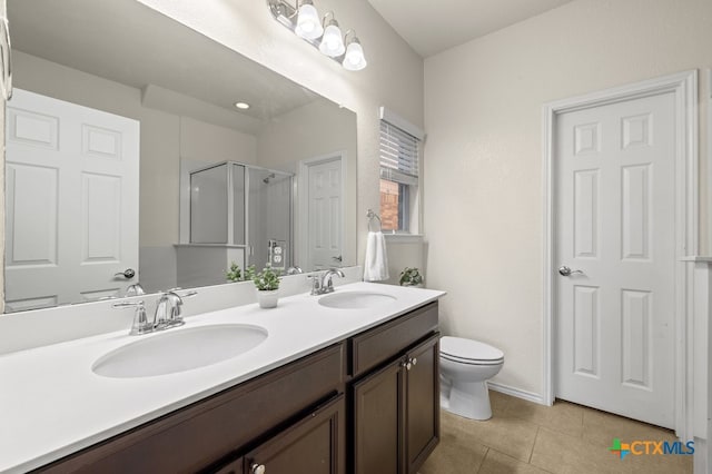 bathroom featuring toilet, vanity, tile patterned floors, and a shower with door