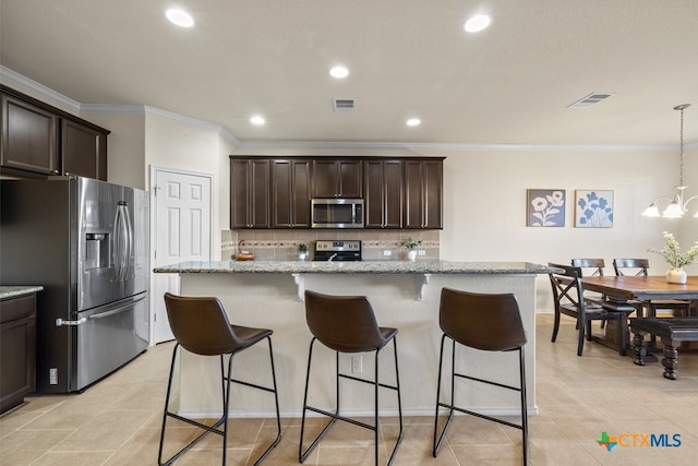 kitchen featuring a center island with sink, stainless steel appliances, light stone countertops, hanging light fixtures, and an inviting chandelier