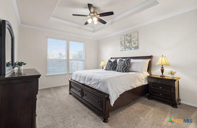 bedroom with light colored carpet, ceiling fan, crown molding, and a tray ceiling