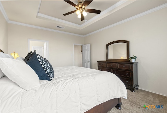 carpeted bedroom with ornamental molding, ceiling fan, and a raised ceiling