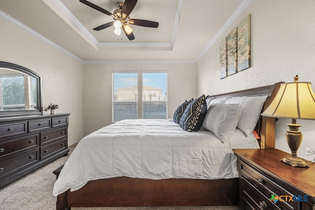 bedroom with ornamental molding, light carpet, ceiling fan, and a tray ceiling