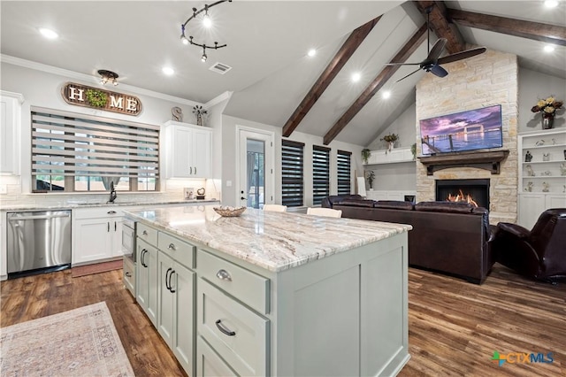 kitchen with stainless steel appliances, a center island, a fireplace, white cabinets, and tasteful backsplash