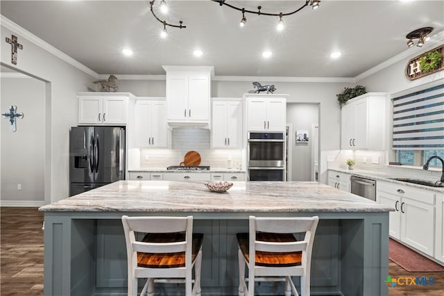 kitchen featuring appliances with stainless steel finishes, white cabinetry, light stone countertops, and a kitchen island