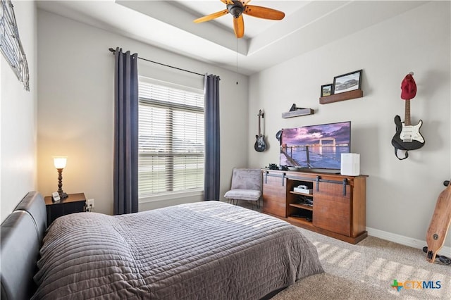 bedroom with ceiling fan, a tray ceiling, and carpet