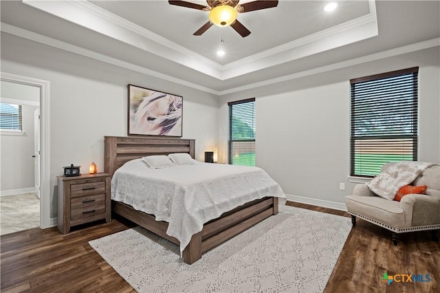 bedroom with a raised ceiling, ceiling fan, crown molding, and dark wood-type flooring