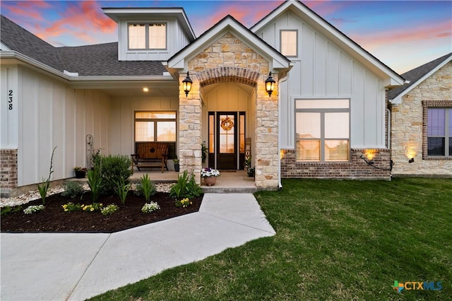 exterior entry at dusk with a yard and covered porch