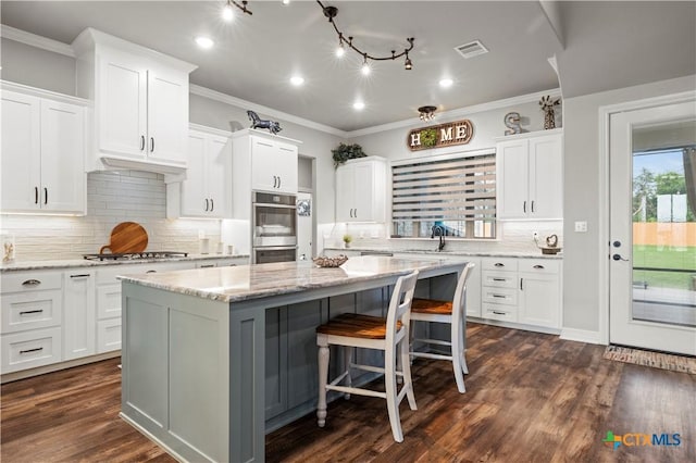 kitchen with stainless steel appliances, decorative backsplash, white cabinetry, and a center island