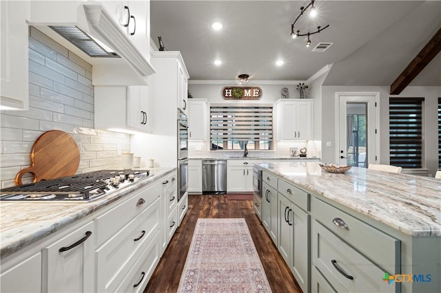 kitchen with stainless steel appliances, light stone countertops, custom range hood, white cabinets, and backsplash