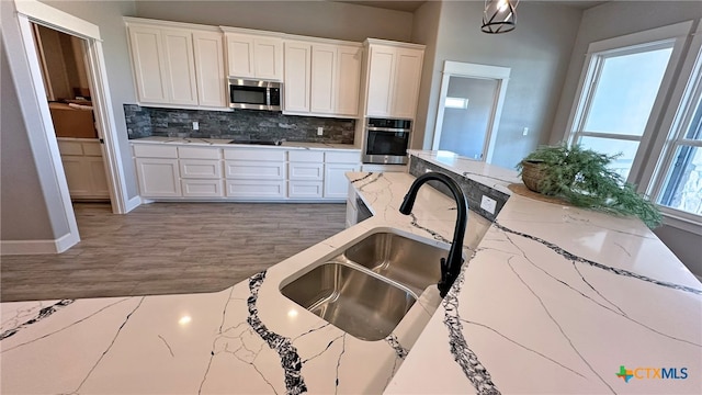 kitchen featuring light stone countertops, white cabinetry, pendant lighting, and appliances with stainless steel finishes