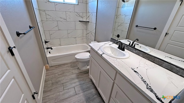 full bathroom featuring toilet, tiled shower / bath combo, vanity, and hardwood / wood-style flooring