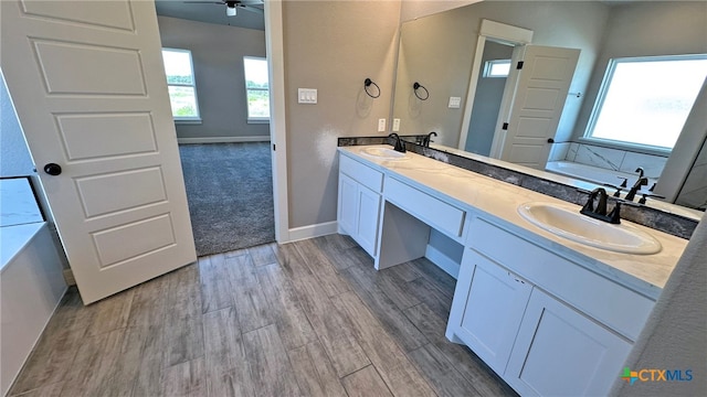 bathroom featuring vanity, a tub, hardwood / wood-style flooring, and a healthy amount of sunlight