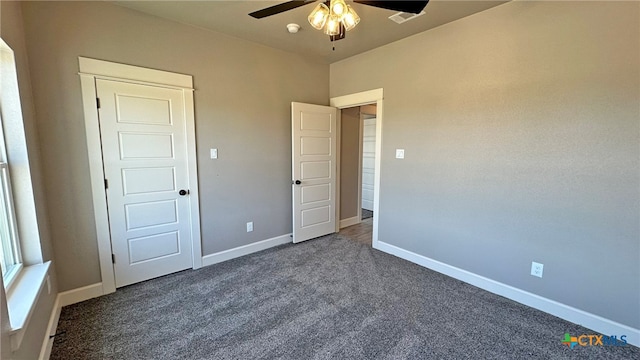 unfurnished bedroom with dark carpet and ceiling fan